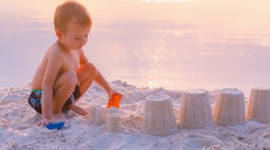 boy building a sand castle on the beach | Coastline Realty Vacations