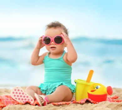 baby girl wearing sunglasses on the beach | Coastline Realty