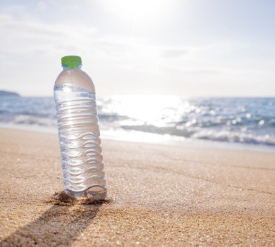 water bottle sitting in the sand on the beach | Coastline Realty