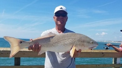 man holding a caught fish on surf city pier | Coastline Realty Vacations